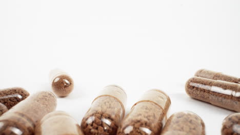 transparent capsules with brown granules on a white surface with selective focus