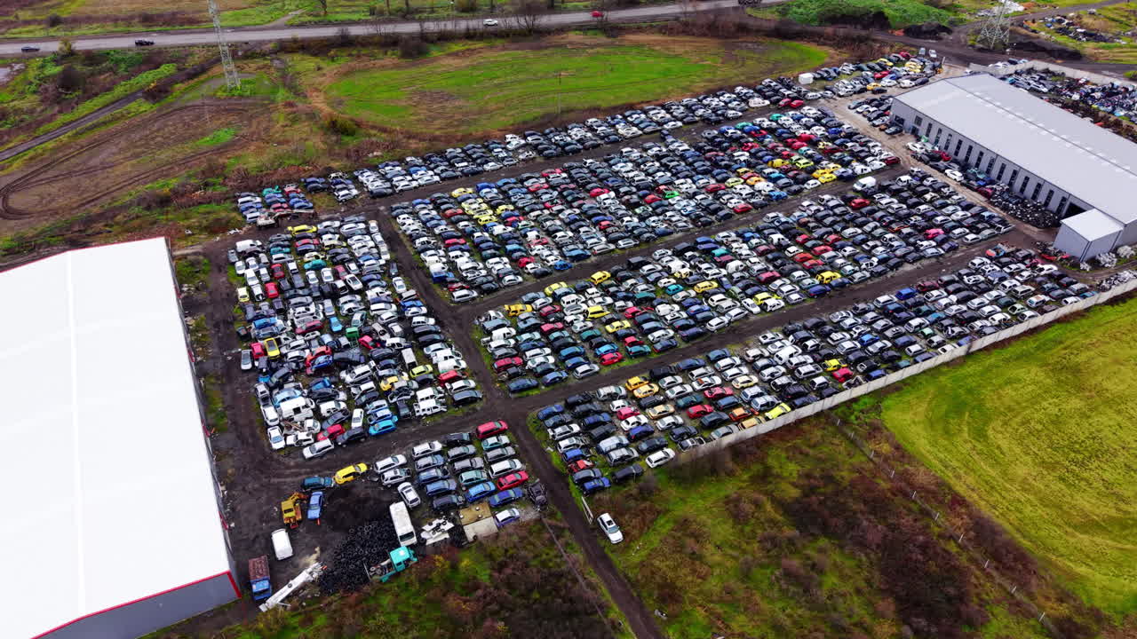 Centinaia di veicoli smontati e recuperati organizzati in file in un impianto di riciclaggio in Bulgaria sotto un cielo nuvoloso. Veduta aerea di un grande sfasciacarrozze automobilistico con diverse auto.