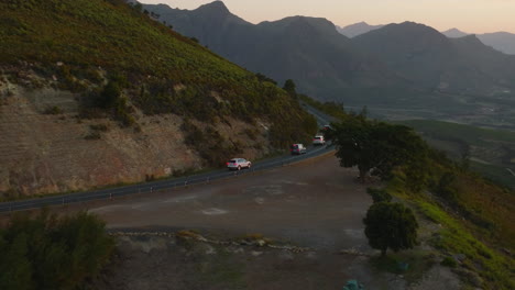 Seguimiento-De-Un-Grupo-De-Automóviles-Que-Conducen-Por-Carretera-En-Las-Montañas.-Vista-Aérea-Del-Paisaje-Por-La-Noche.-Sudáfrica