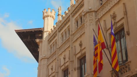 flags waving on the facade of town hall in palma de majorca, spain. low angle shot