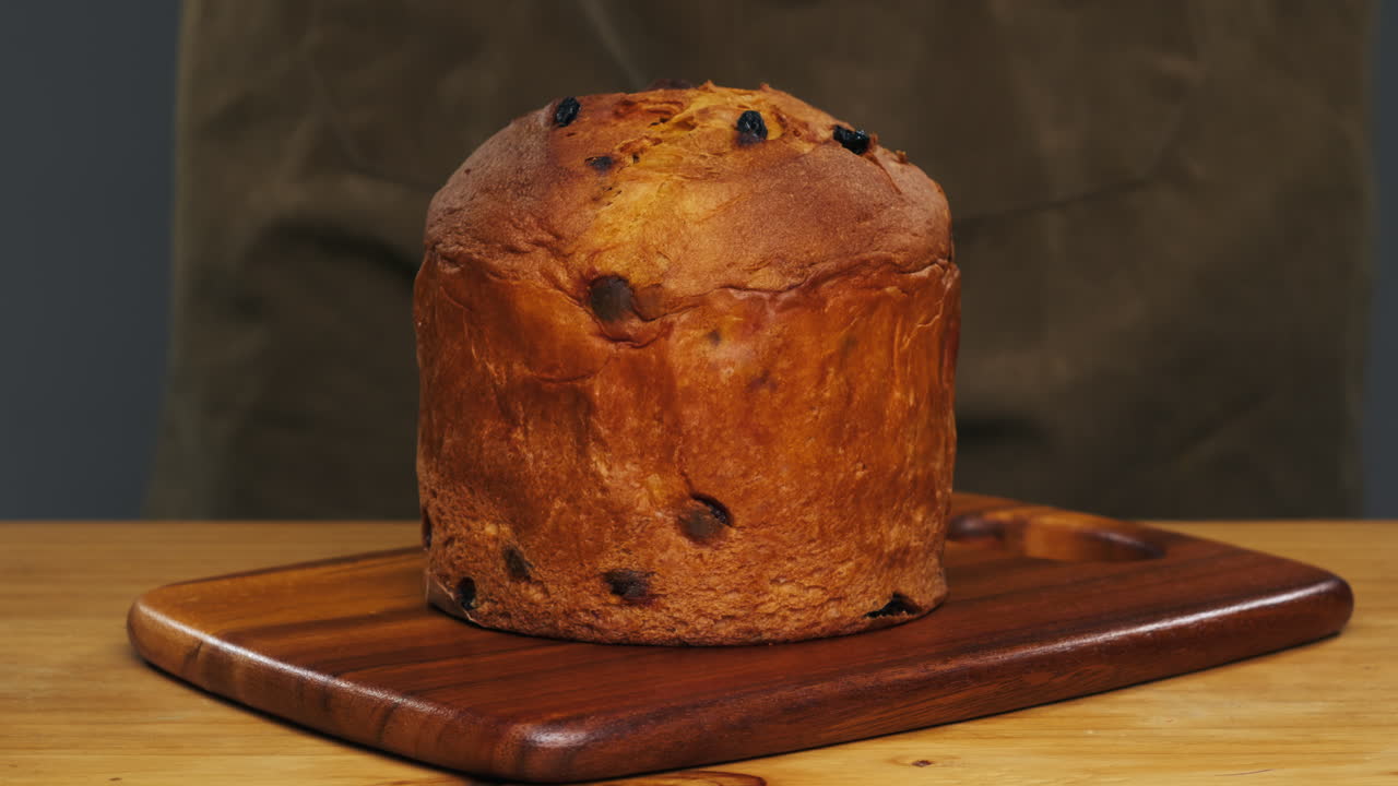 Traditional English Christmas cake tied with a jute thread on the black background. Italian classic Panettone .Pastry Chef sprinkles powdered sugar through a sieve on the fruit Easter cake with raisins. High quality 4k footage