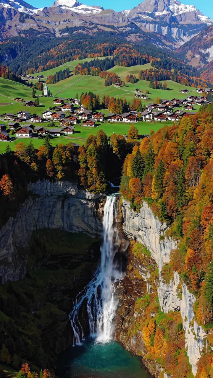 Vista aerea di un video di una cascata impetuosa circondata da una lussureggiante vegetazione autunnale e da un pittoresco villaggio