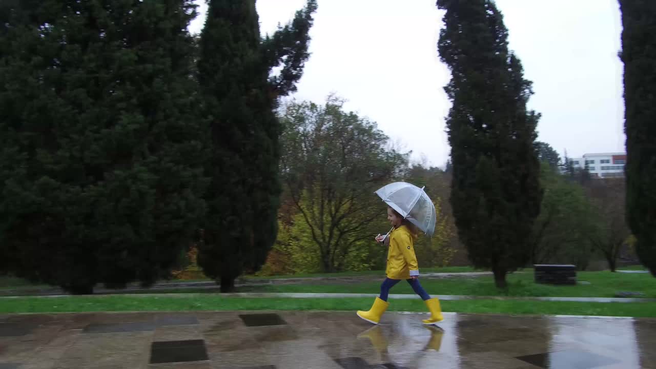 Glad kid jumping along street on rainy day
