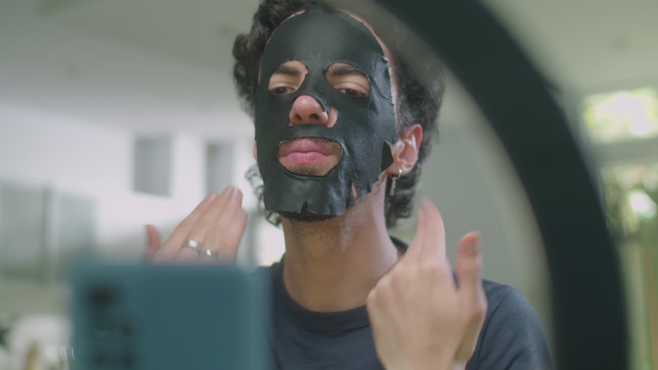 Male Beauty Vlogger Using Sheet Mask while Going Live