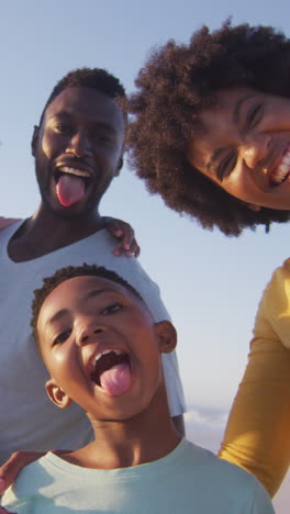 portrait of smiling african american family looking at camera on sunny beach