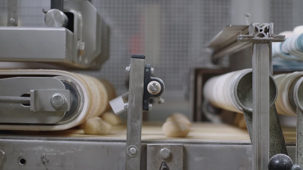 Fresh Bread Dough Balls Moving Along On Conveyor Belt. Low Angle, Side View