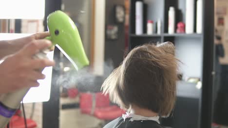 young woman getting her hair dressed in salon. hair stylist hairdresser with hair dryer applying spray. beauty salon. shot in