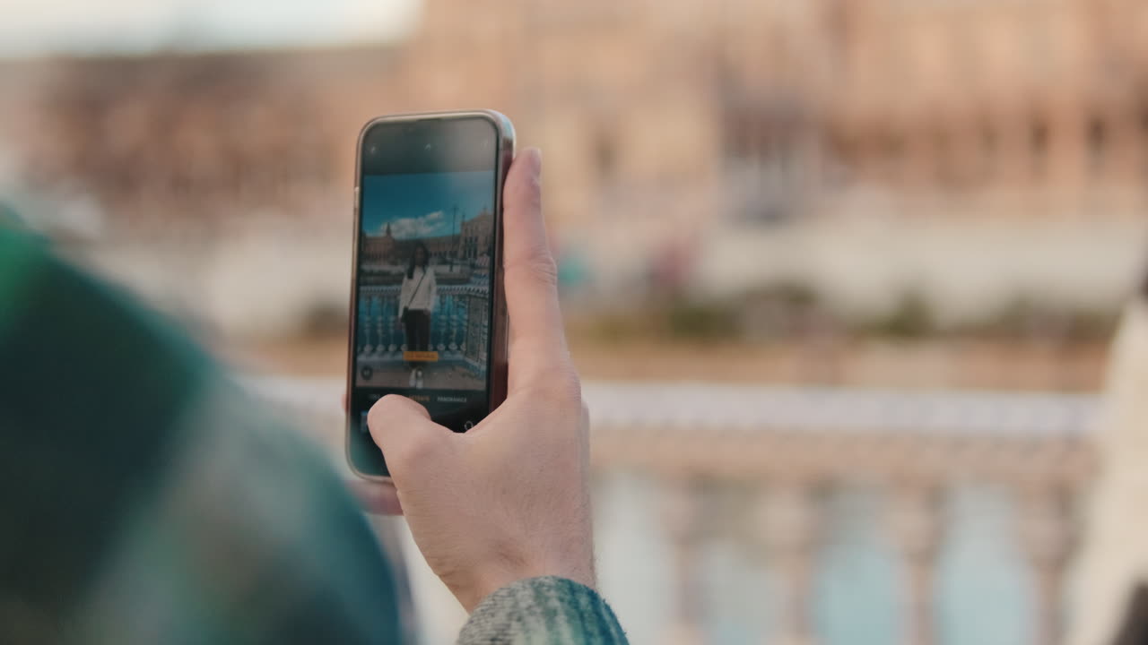 Close up of man's hand holding mobile phone, taking photo of girlfriend