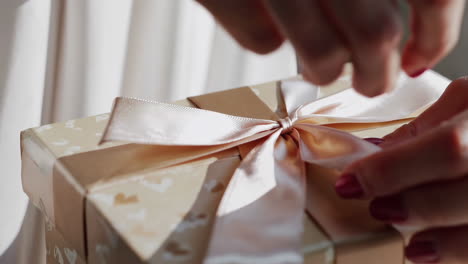 close-up of hands tying a ribbon on a gift box
