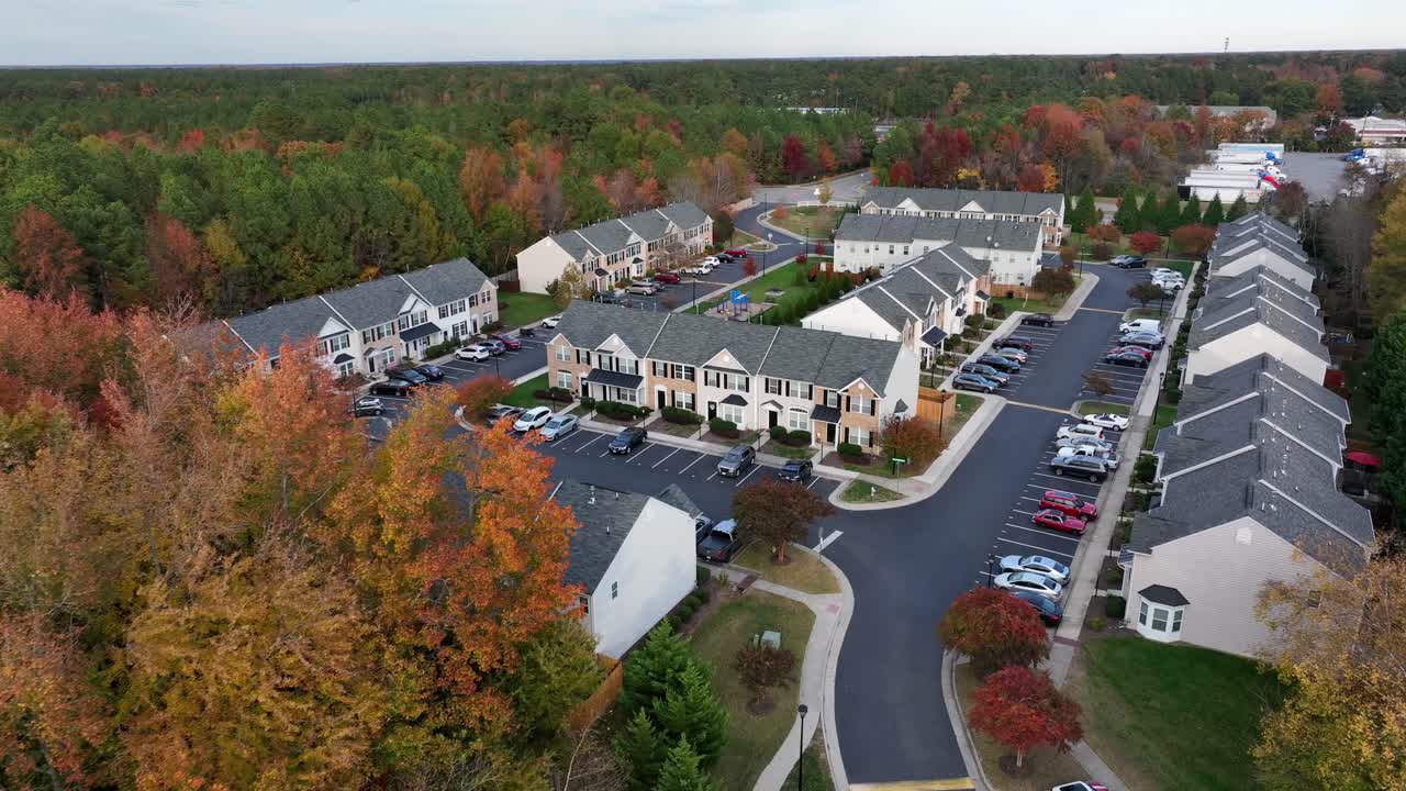 Comunità americana nella periferia della città. Alberi colorati in autunno. Case a schiera e condomini con balcone e patio. Ripresa aerea. Auto parcheggiate nella zona. Quartiere tranquillo negli USA