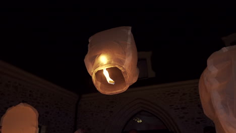 Sky-lanterns-glowing-in-the-night-sky-with-a-historic-building-in-the-background