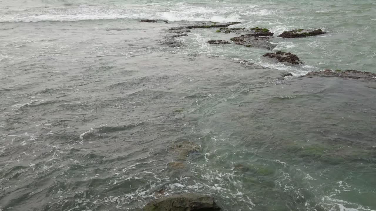 파도가 해안의 얕은 바위 해안으로 굴러가고 정적 샷