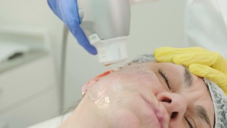 professional face skin rejuvenation, lifting procedure. cosmetologist uses modern ultrasound device. hardware cosmetology