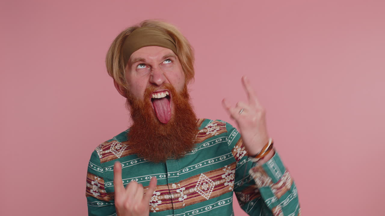 Man with red beard and headband making rock on hand gesture