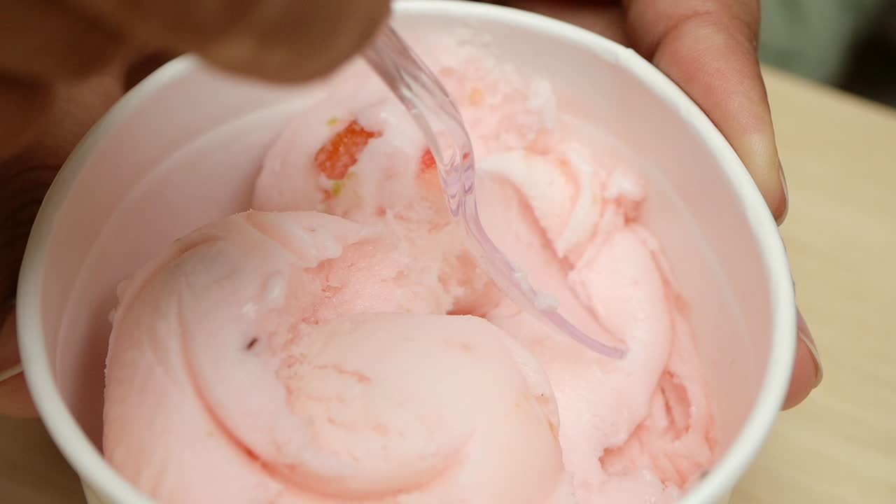 Mangiare una pallina di gelato rosa alla fragola