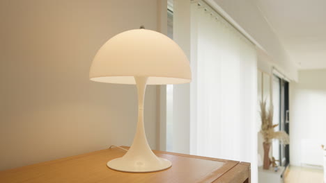 minimalist white table lamp on a wooden desk in a bright room