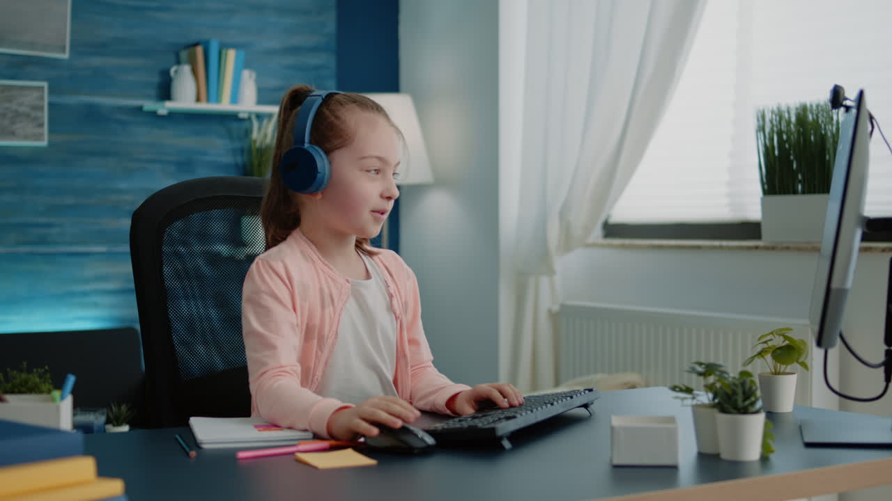 Child waving at video call webcam on computer for school work