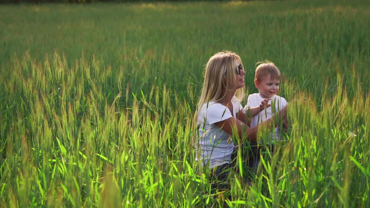 счастливая семья веселится. мальчик с коричневыми кудрявыми волосами и его мать с рыжими волосами показывают палец друг другу. съемка на открытом воздухе