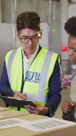 diverse male and female workers with clipboard and boxes in warehouse