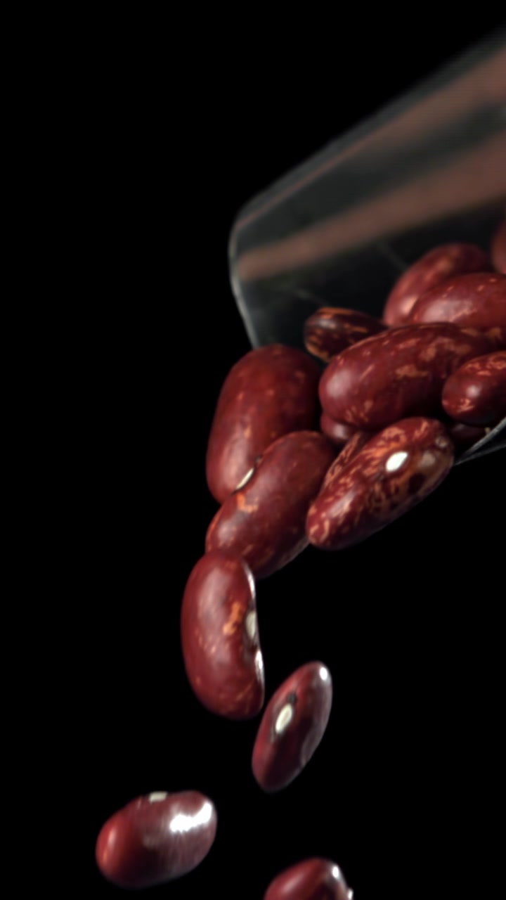 Red Kidney Beans Falling in Slow Motion Against Black Background