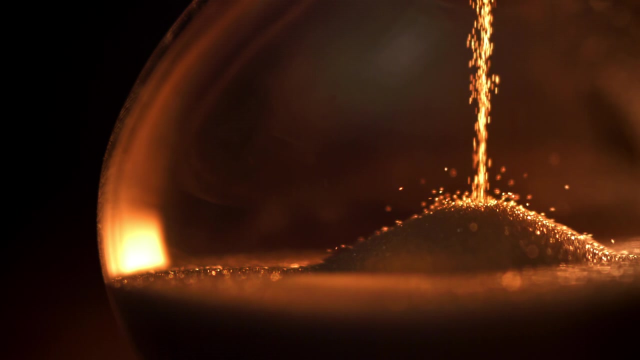 Golden Sand Falling in an Hourglass with Warm Light