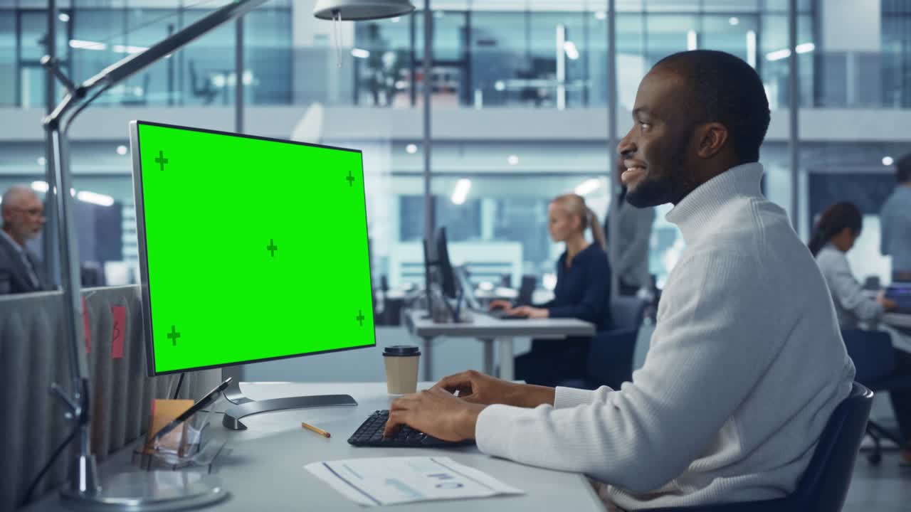 Diverse Modern Office: Handsome Black Businessman Using Desktop Computer with Green Screen Mock Up Display. Manager Working on e-Commerce App Development, Project Marketing, Big Data Analysis