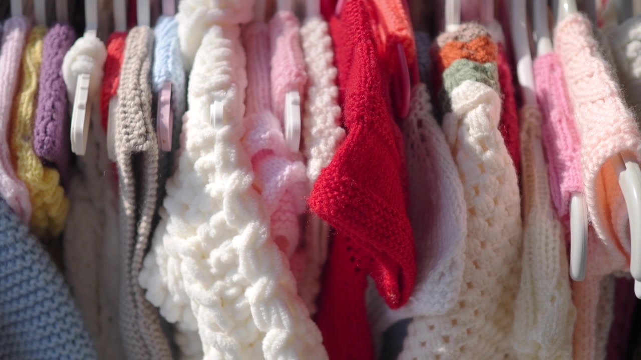 Assortimento di vestiti per neonati lavorati a maglia a mano appesi a uno stendino