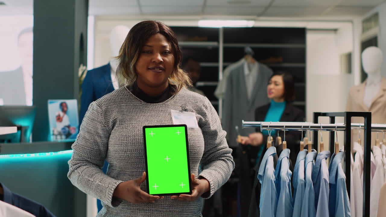 Kvinde viser en tablet med en grøn skærm i en tøjbutik