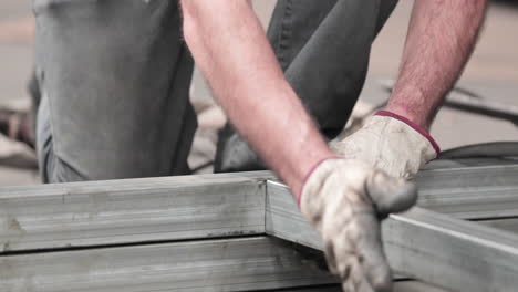 steel worker assembling metal frame made of gi tubular - close up