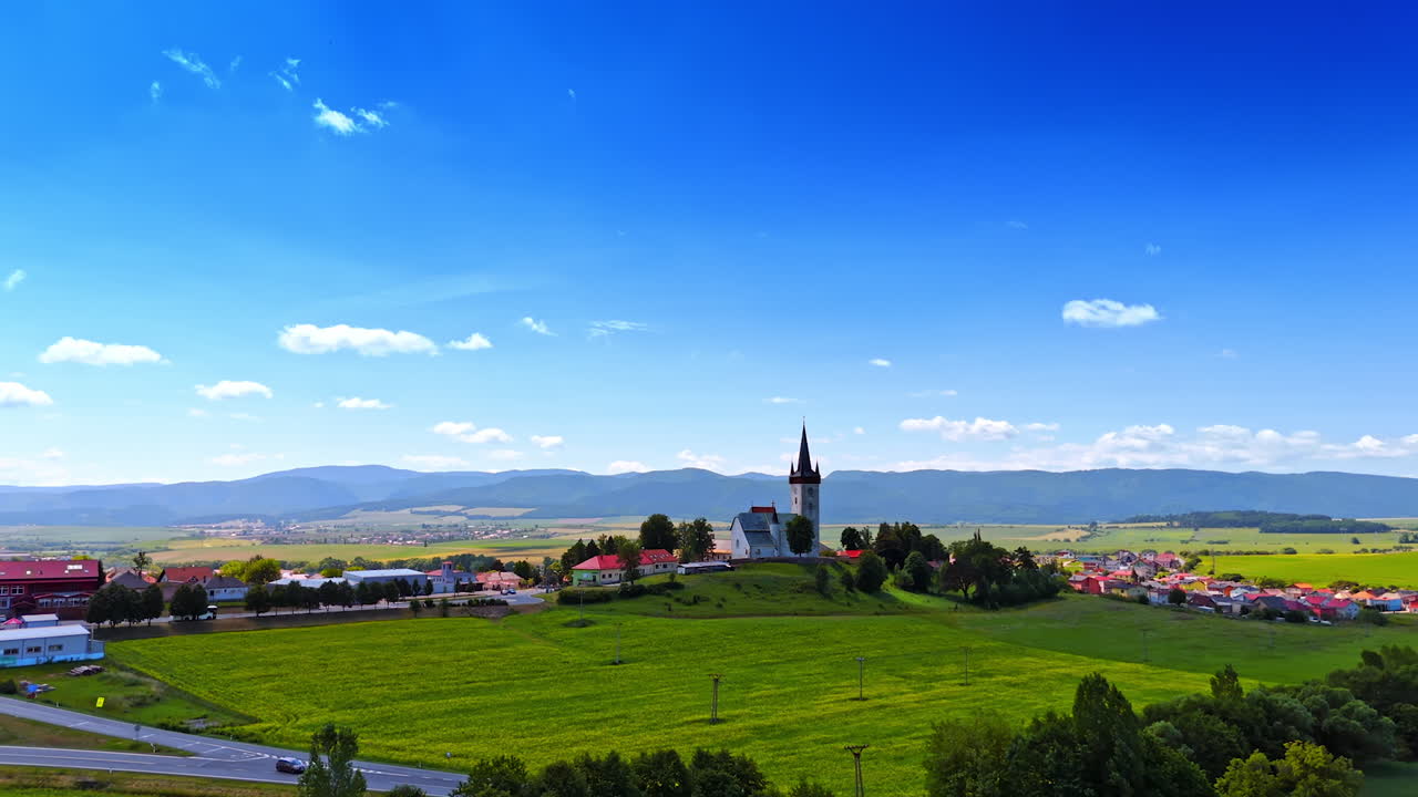 Picturesque valley surrounded by the mountain range. Approaching the old church located on the hill. Slovakia.