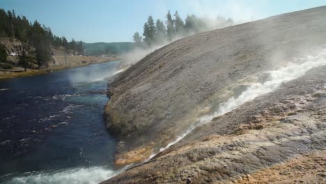el agua caliente al vapor entra en el río firehole en las aguas termales prismáticas en el parque nacional de yellowstone