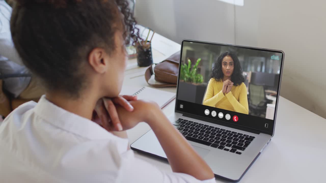 mujer afroamericana usando una computadora portátil para una llamada de video, con un colega de negocios en la pantalla