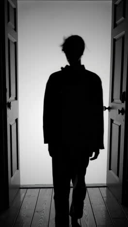 silhouette of a person walking through a doorway