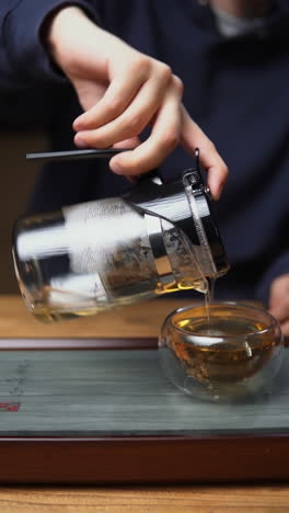 pouring tea into a glass teacup