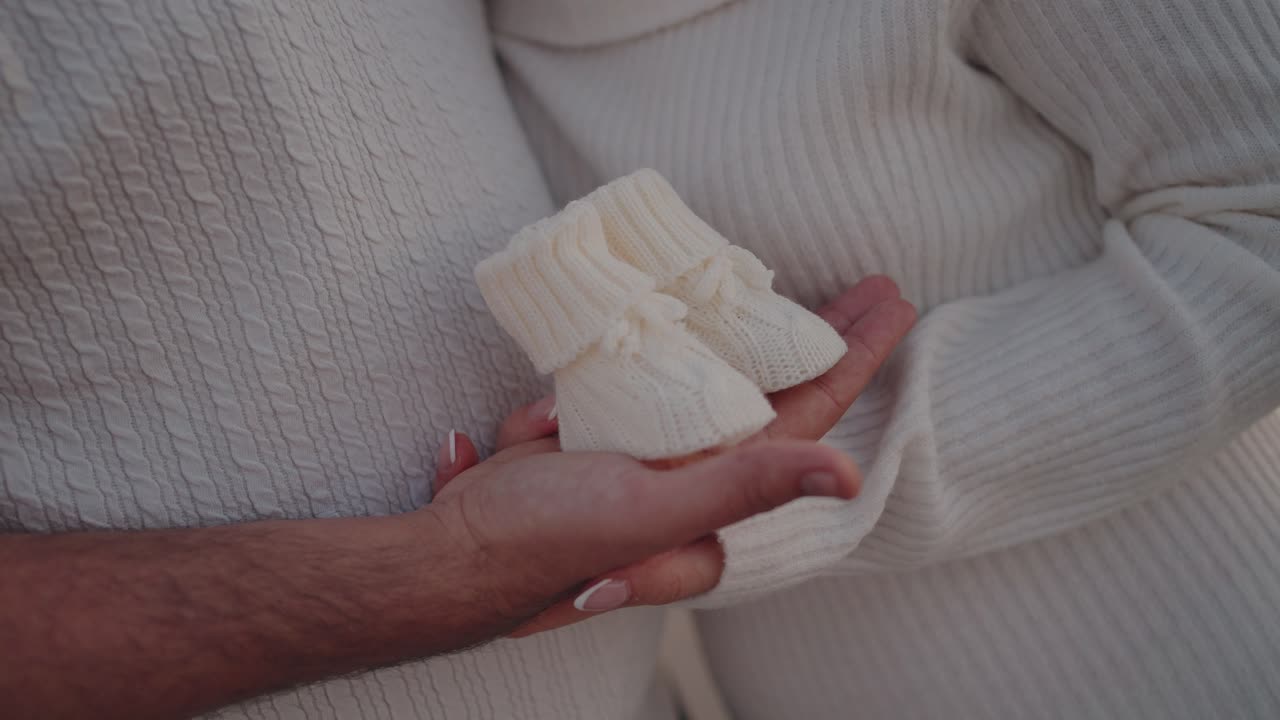 사랑과 새로운 시작을 상징하는 아기 부티를 함께 들고 있는 커플의 클로즈업