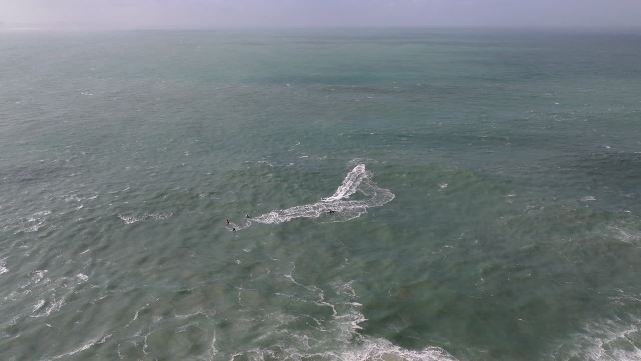 Aerial drone shot of jet ski riders and surfers waiting for waves in the Atlantic Ocean on a day with giant waves in Nazaré, Portugal, Europe. Big wave surfing town, iconic sports surfing location