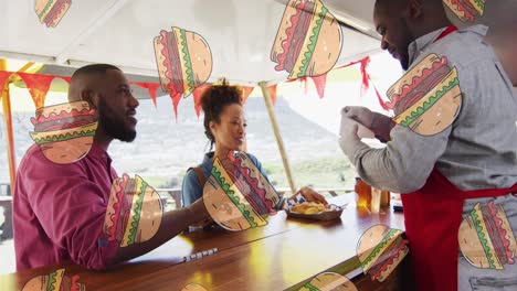 animation of hamburgers over african american male food vendor serving smiling customers