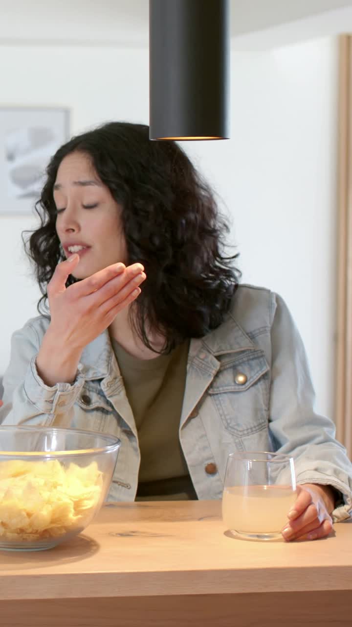 Vertical video: Talking on offframe prompt, woman in denim jacket gesturing at bar with chips glass