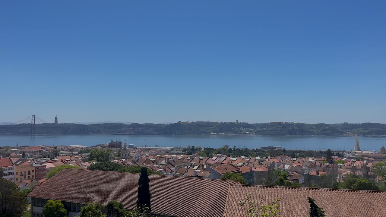 A stunning time-lapse of Lisbon, Portugal, capturing the river, 25 de Abril Bridge, iconic cityscape under a clear blue sky. The scene showcases the harmonious blend of urban and natural landscapes.