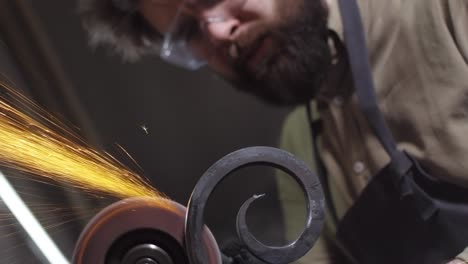 handsome blacksmith using automatic hand emery