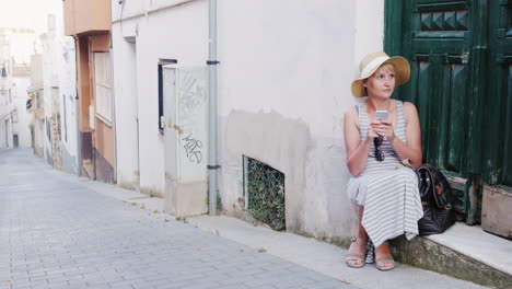 woman tourist uses smartphone he is sitting on the threshold of the old house in the resort town con