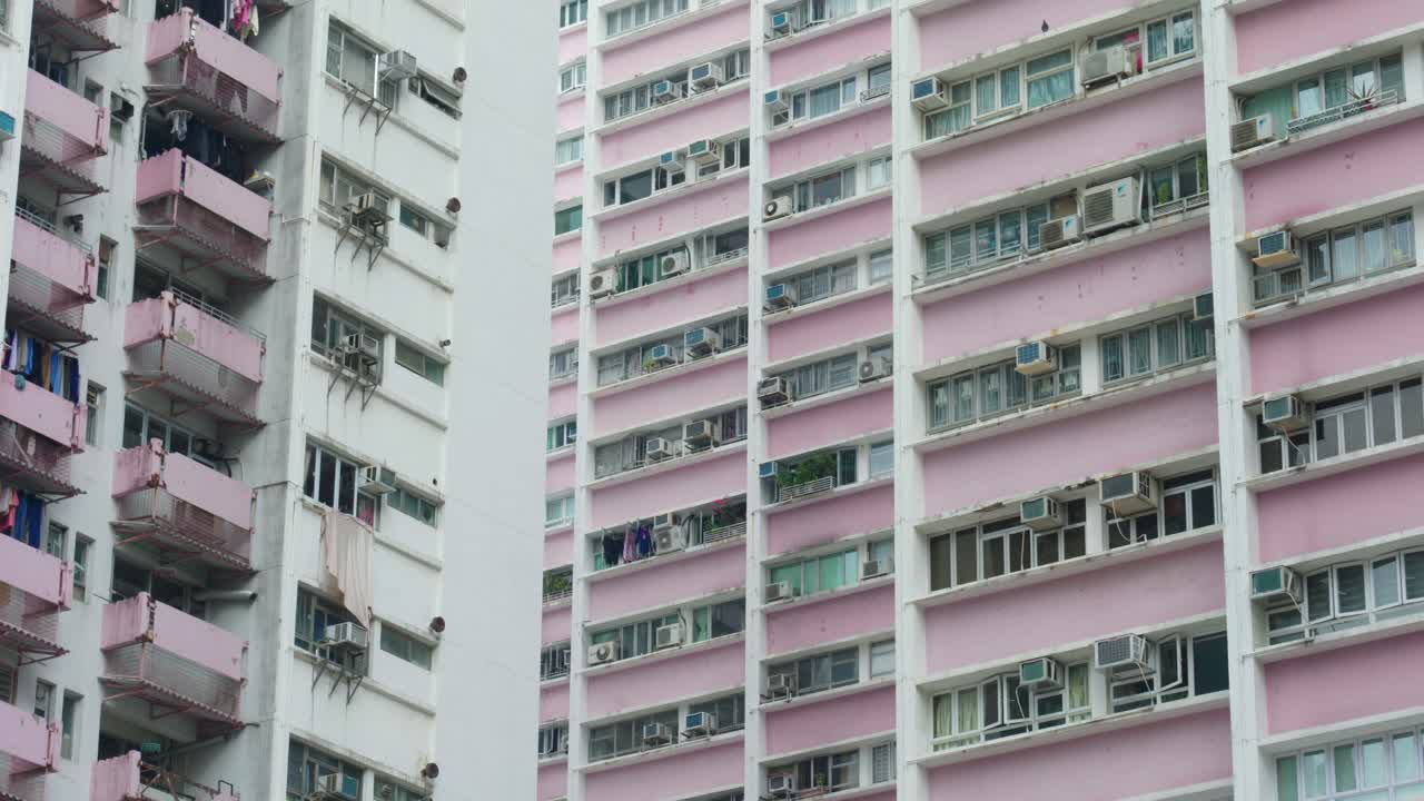 Vista panorâmica de edifícios de apartamentos e arranha-céus no centro de Hong Kong, China, em um dia ensolarado, mostrando a densidade da vida urbana e a arquitetura moderna.