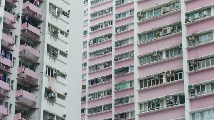 Vista panorâmica de edifícios de apartamentos e arranha-céus no centro de Hong Kong, China, em um dia ensolarado, mostrando a densidade da vida urbana e a arquitetura moderna.
