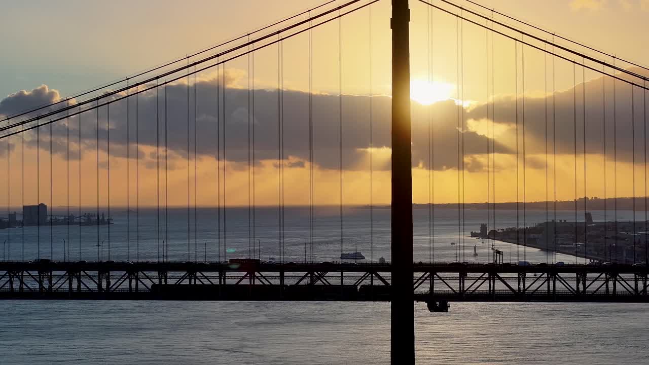Sunset Skyline Of 25Th April Bridge At Lisbon In District Of Lisbon Portugal. Sunset Cityscape. Cable Bridge Scene. 25Th April Bridge At Lisbon In Portugal. Train In Bridge Landscape. Elevated Road.