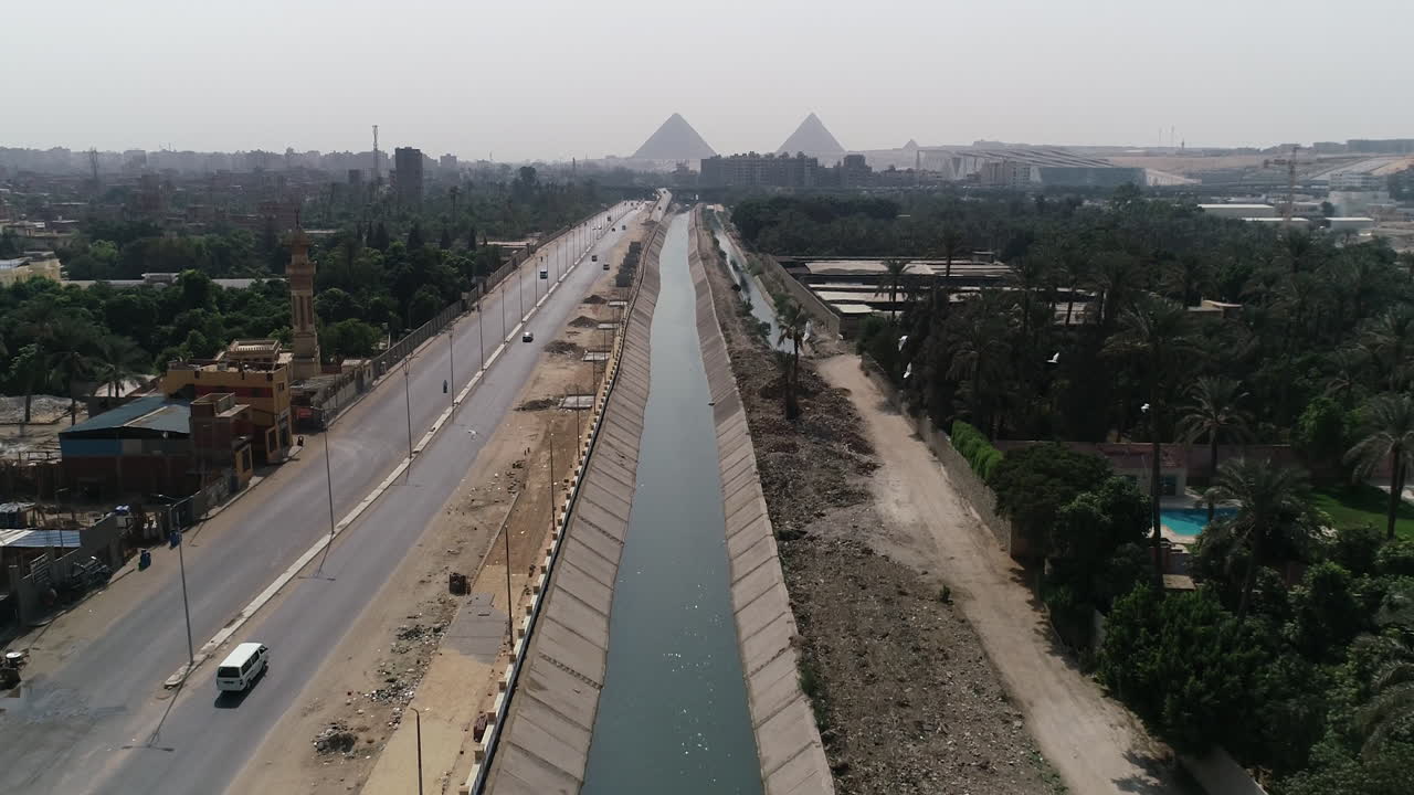 pista de disparo aéreo hacia fuera y subiendo para las pirámides de egipto en giza en el fondo de una rama del río nilo en el primer plano rama de maryotya y los pájaros están pasando en el frente