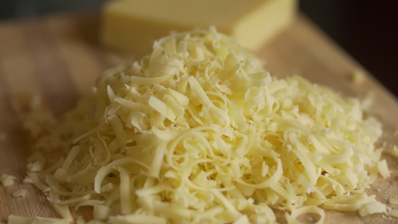 Revealing shot of cheese grated in a chopping board