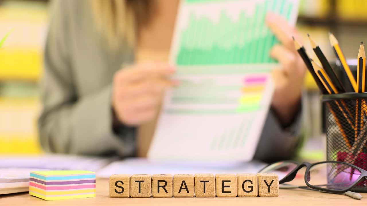 Holzwürfel buchstabieren Strategie, während Geschäftsfrau Aufgaben plant.