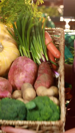 personal masculino ayudando a una mujer a comprar verduras en la sección orgánica