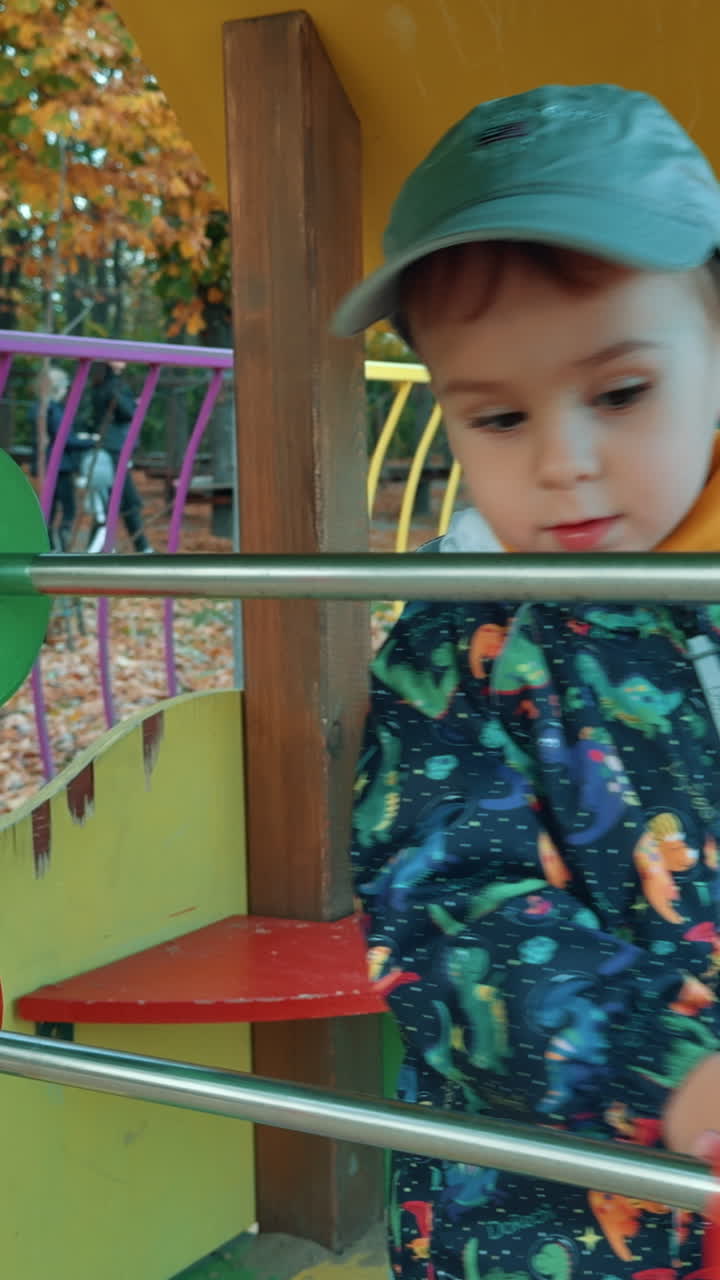 Lovely Caucasian toddler playing with big abacus on the playground. Male kid having good time outdoors in autumn. Vertical video
