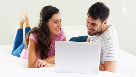 Couple-interacting-with-each-other-while-using-laptop-on-bed